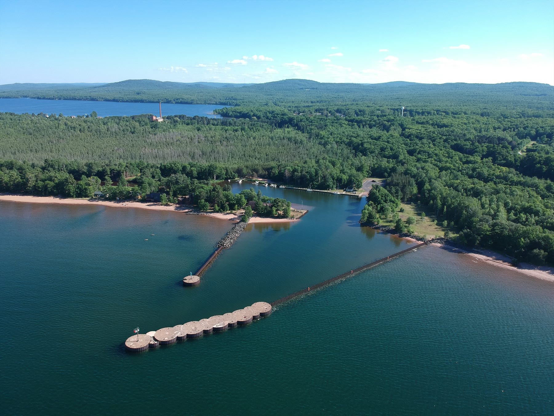 Aerial view of a forested harbor extending into blue water