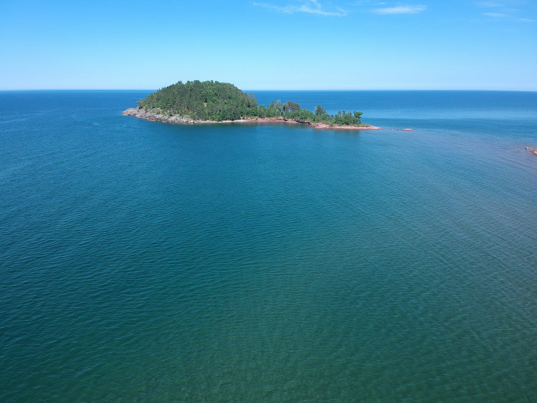 Small forested island surrounded by broad blue water
