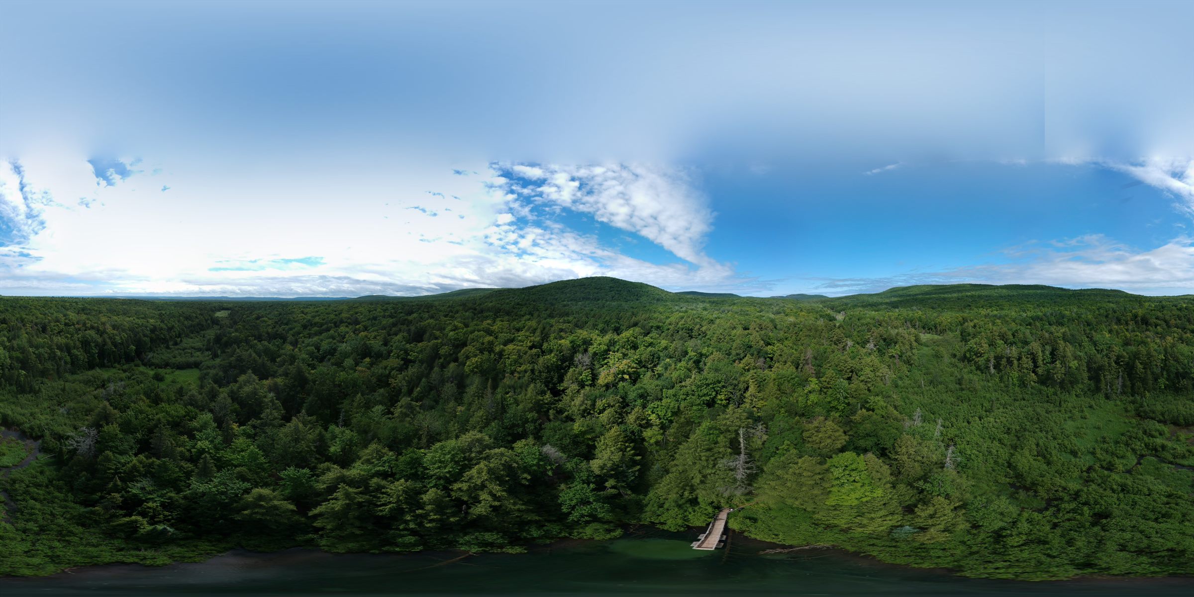 Panoramic aerial view of forested Upper Peninsula terrain under a broad blue sky