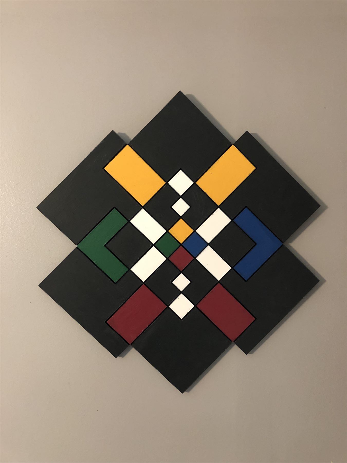 Layered chromatic geometric wall object formed from rotated squares and a central star