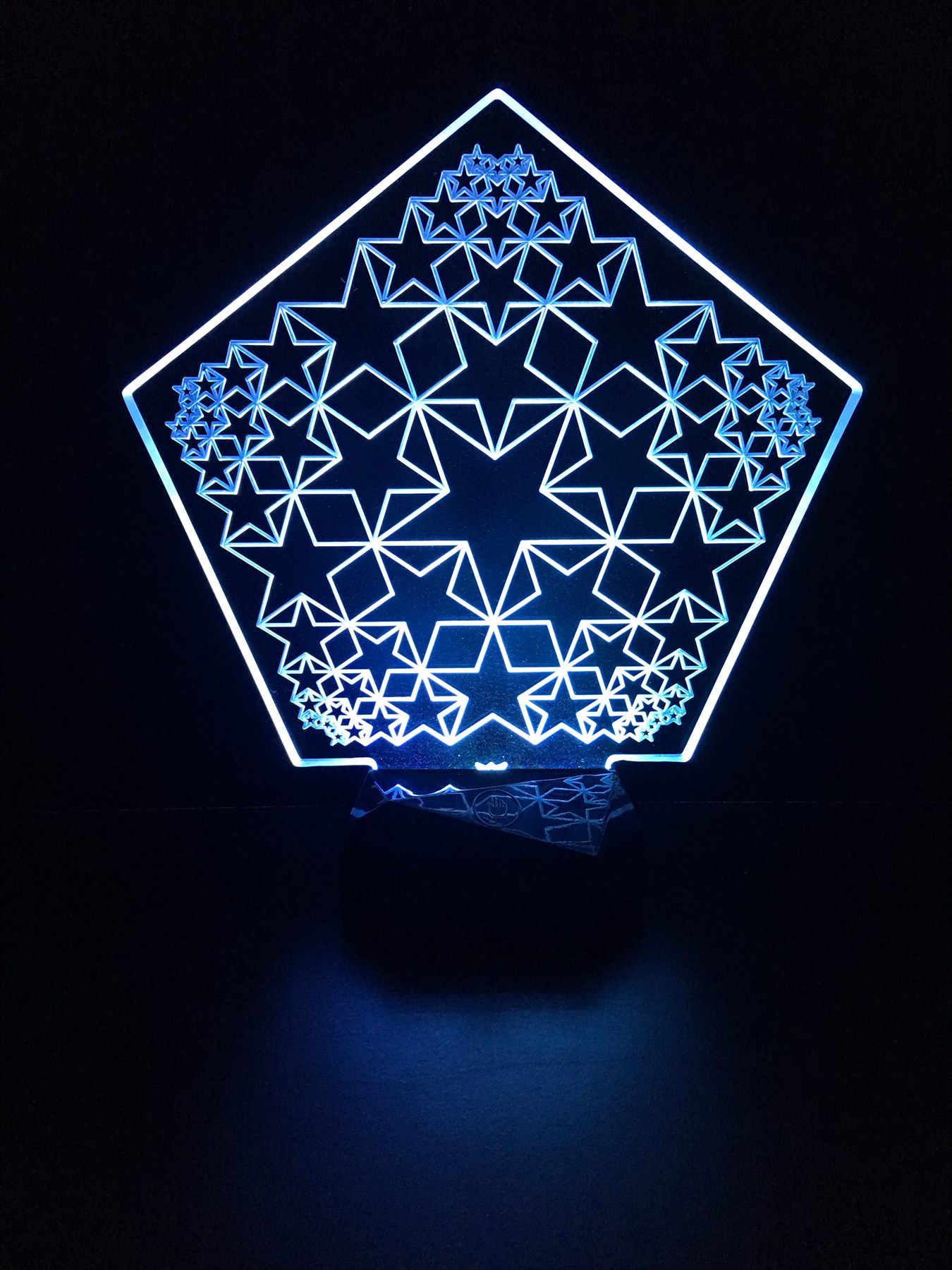 Blue illuminated pentagonal acrylic panel engraved with recursive stars