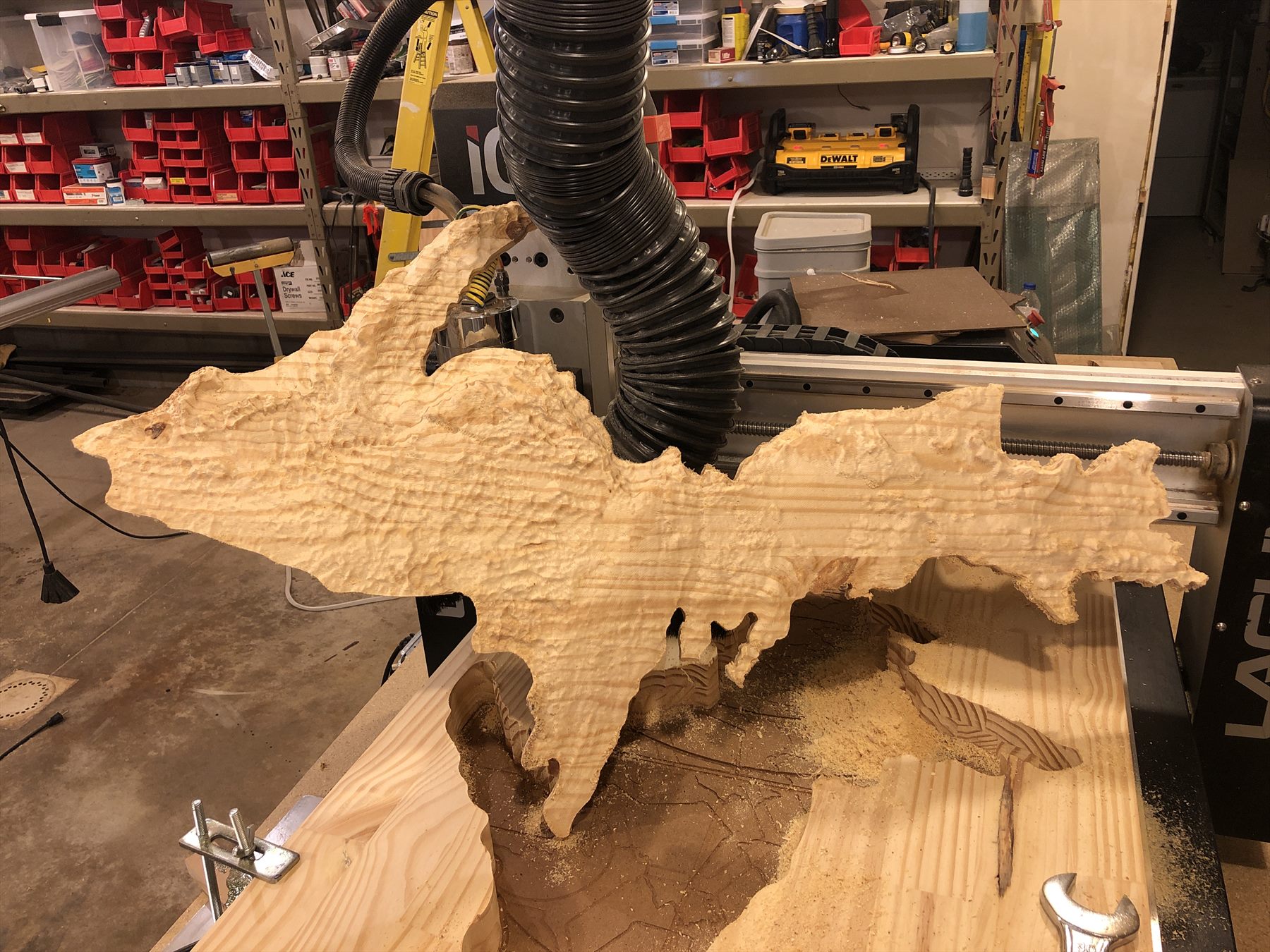 Natural-edge wood slab being shaped beneath a CNC dust collection head