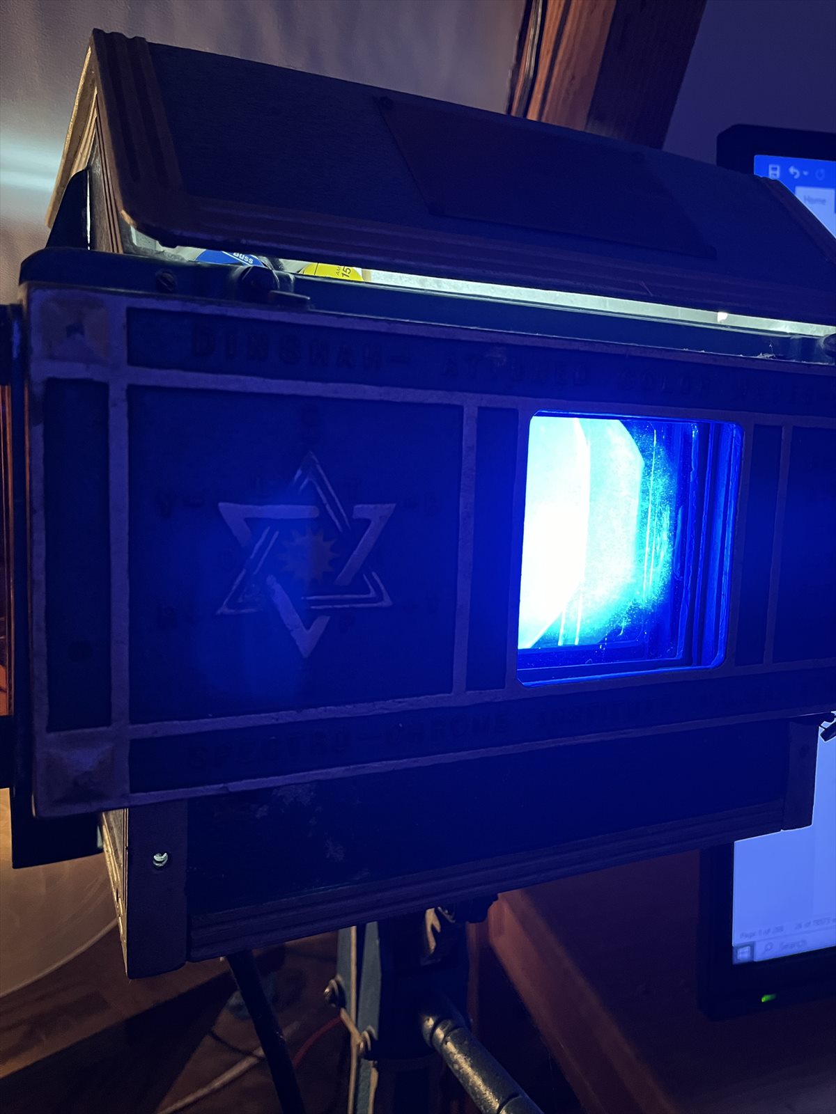 Vintage Spectro-Chrome projector inherited from Eugene Nagy, glowing blue with its wooden lid raised and colored glass slides visible.