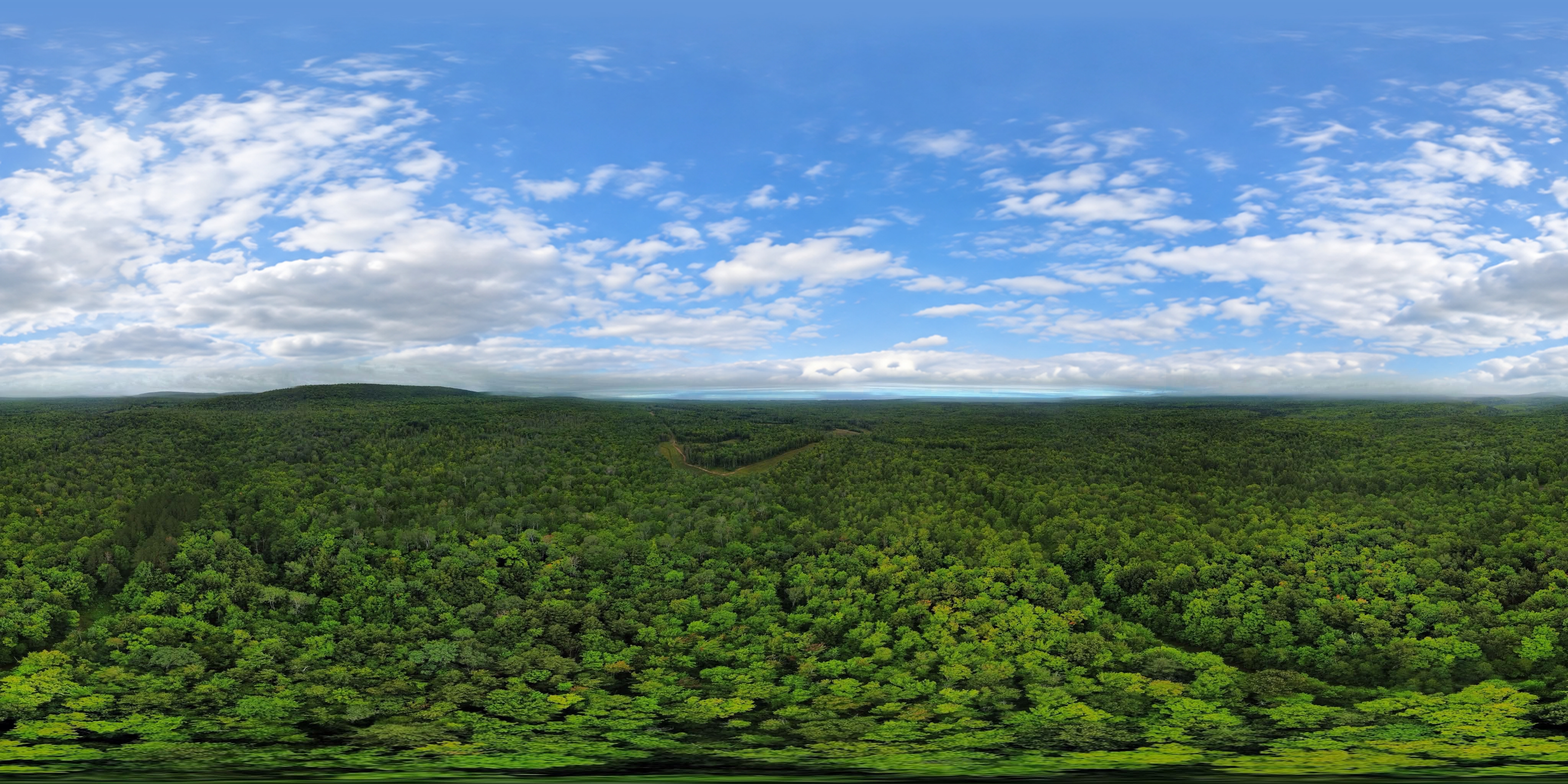 Ryan Nagy's aerial panorama of forest canopy and worked ground near Copperwood, with Lake Superior on the distant cloudy horizon.